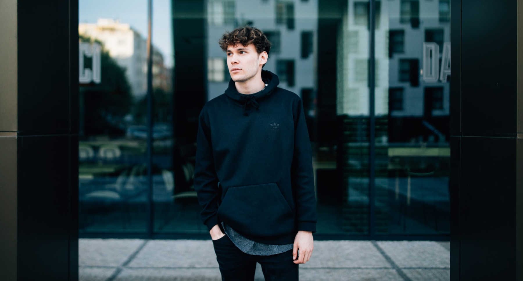 boy in black hoodie in front of building
